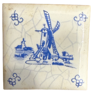 Blau-weiße niederländische Fliese mit Windmühle, Kirche und Spinnenkopf-Eckmotiven, Craquelé-Glasur; daneben gerippte Rückseite und Kartondöschen von A. Driessen, Rotterdam
